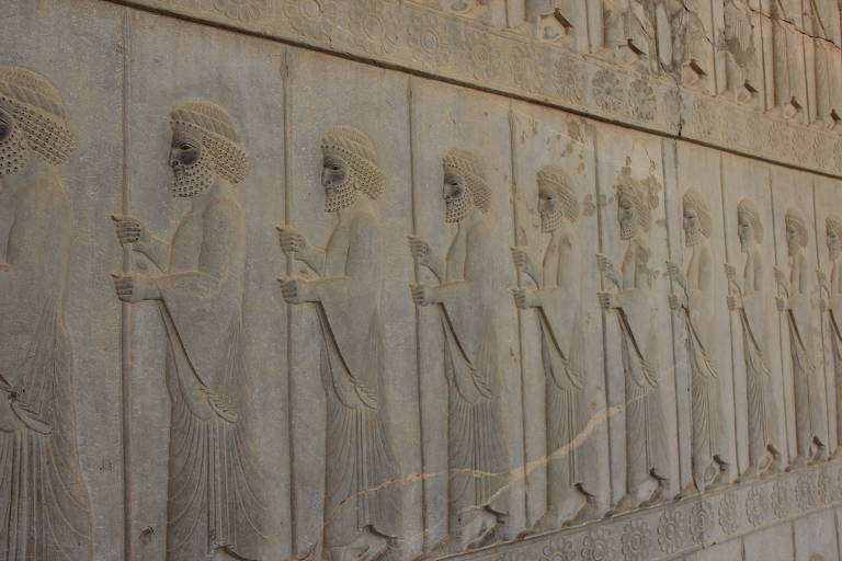 Parede antiga com desenho de soldados persas com lanças