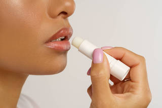 African woman apply hygienic balsam lipstick for lips moisturizing and protection from cold and wind