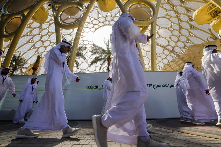 Homens com vestes árabes brancas caminham em corredor decorado