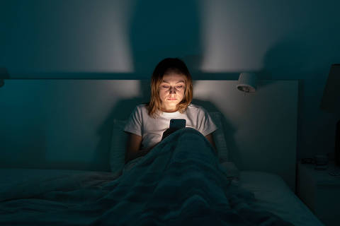 Sleepy exhausted woman lying in bed using smartphone, can not sleep. Insomnia, addiction concept. Sad girl bored in bed scrolling through social networks on mobile phone late at night in dark bedroom. - (Photo: DimaBerlin/stock.adobe.com)
