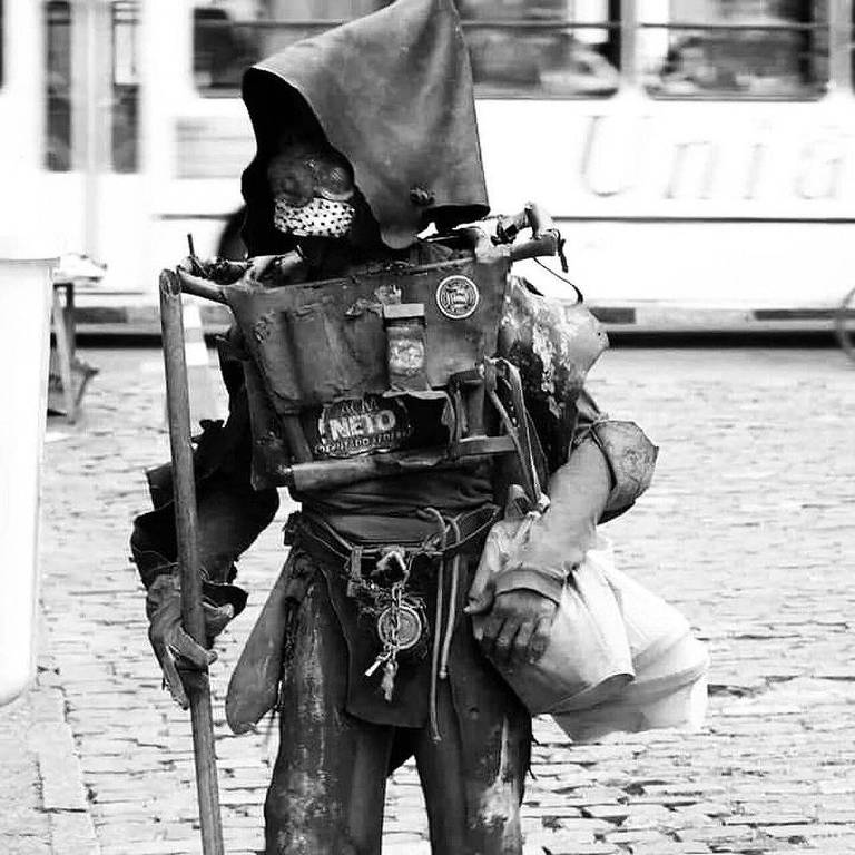 Artista plástico Jayme Figura (1959-2023) vestido com armadura de metal andando em calçadão