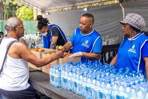 Atendente de tenda da Operação Altas Temperaturas entrega fruta para um paulistano; ação já realizou mais de 325 mil atendimentos