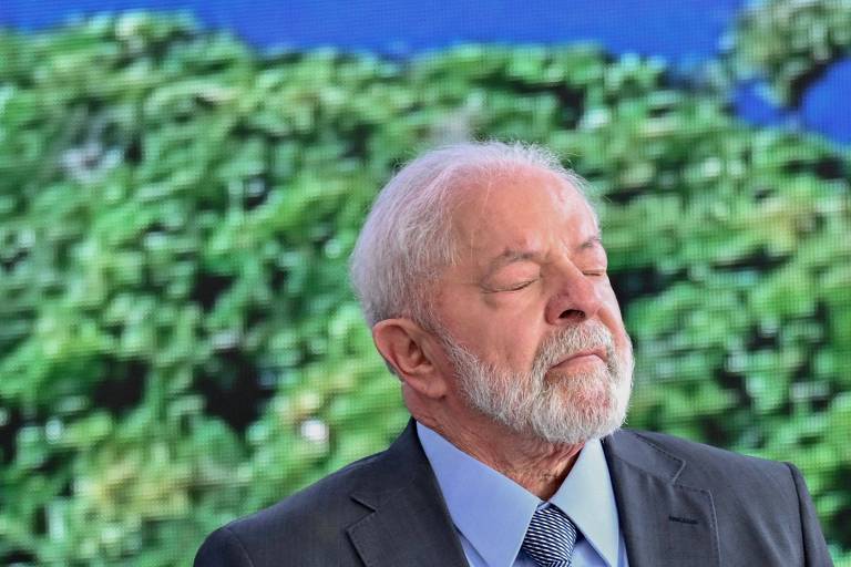 Imagem mostra Lula de olhos fechados na frente de plantas. Ele veste terno.