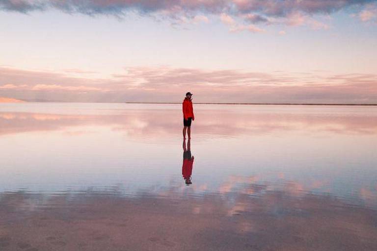 Imagem de uma pessoa caminhando solitária na praia