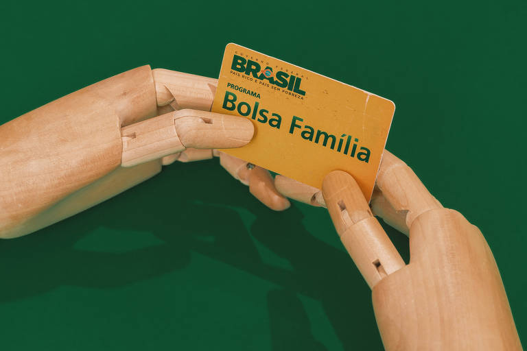 Mãos de madeira segurando Cartão Bolsa Família. sobre um fundo verde escuro