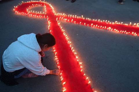 Volunteers light candles arranged in a red ribbon shape during an awareness event organised on the eve of World AIDS day in Kathmandu on November 30, 2023. (Photo by PRAKASH MATHEMA / AFP)