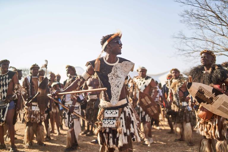 Jovens com peles de animais e escudos de madeira que são vestes tradicionais africanas