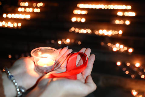 (231201) -- BEIJING, Dec. 1, 2023 (Xinhua) -- People hold a candle and a red ribbon during an event to raise awareness of AIDS at University of South China in Hengyang, central China's Hunan Province, Nov. 29, 2023. The World AIDS Day falls on Dec. 1. (Photo by Cao Zhengping/Xinhua)