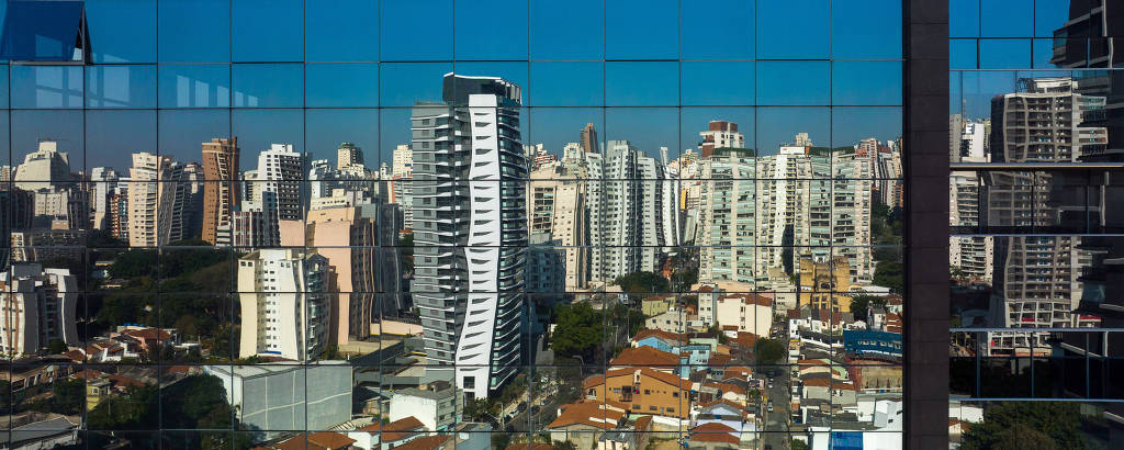 Imagem mostra prédios com formas distorcidas por estarem refletidos em janelas de um edifício