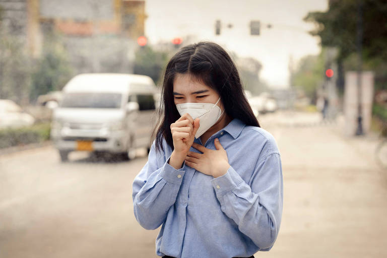 Mulher asiática usando a máscara de proteção respiratória N95 contra poluição do ar 