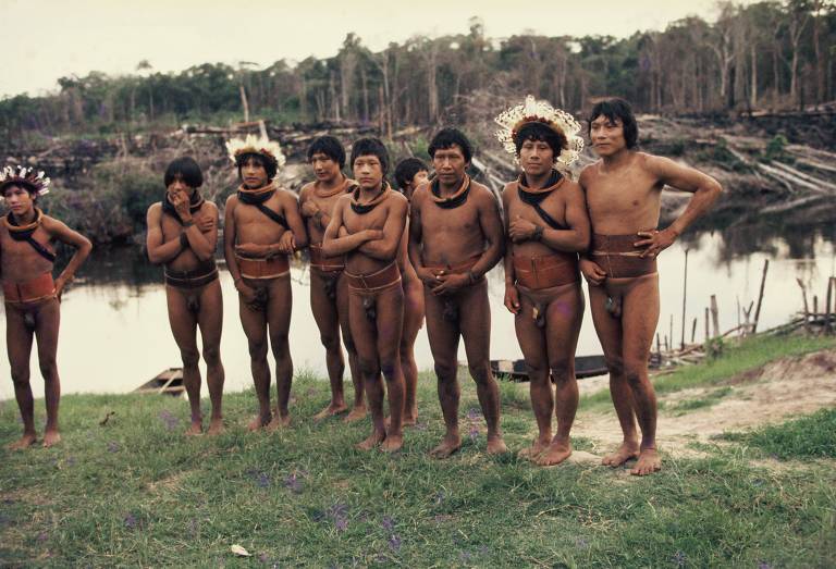 Grupo de pessoas indígenas da etnia cinta-larga; ao fundo há um lago