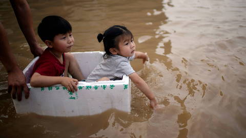FILE PHOTO: Children sit in a styrofoam container on a flooded road following heavy rainfall in Zhengzhou, Henan province, China July 22, 2021.  REUTERS/Aly Song/File Photo ORG XMIT: FW1
