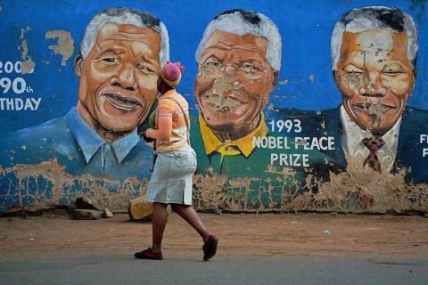 (FILES) Residents walk past murals of late South African former president Nelson Mandela in Soweto, near Johannesburg, on December 7, 2013, two days after his death. Anti-apartheid hero Nelson Mandela has been seen as a moral compass in his home South Africa, but ten years after his death his legacy is vigorously debated, with some questioning the quality of the country's democracy. (Photo by Carl DE SOUZA / AFP) ORG XMIT: CDS1014