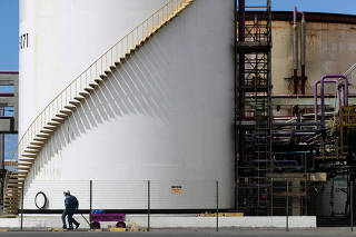 FILE PHOTO: Workers pass in front of a tank at a chlorine-soda plant of the petrochemical company Braskem in Maceio