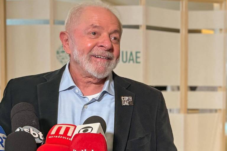  Lula sorri com microfones à sua frente