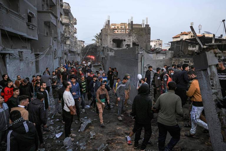 Palestinos ao redor de destroços após ataque aéreo na região de Rafah, no sul da Faixa de Gaza, próximo à fronteira com o Egito