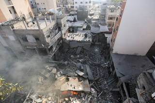 Palestinians inspect a house destroyed in an Israeli strike, in Khan Younis