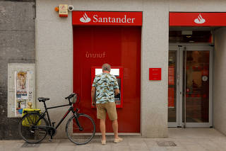 FILE PHOTO: A man uses an ATM machine at a Santander bank branch in Ronda