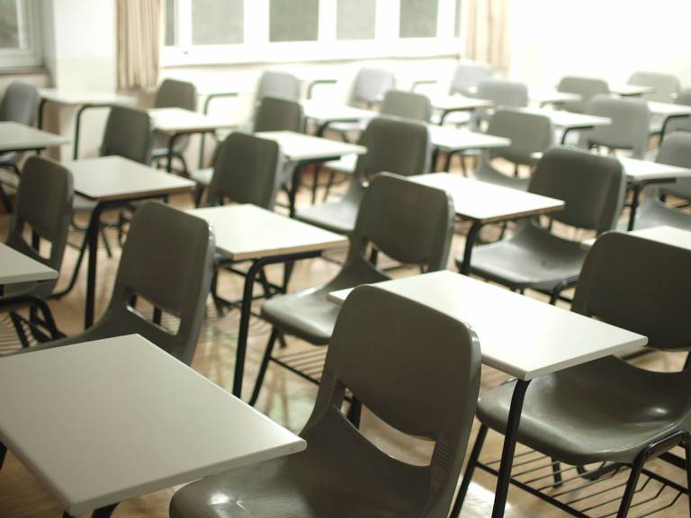 A imagem mostra uma sala de aula com mesas vazias