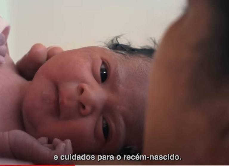 Bebê branco recém-nascido com cabelos pretos e olhos pretos olha para sua mãe