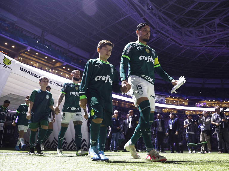 O capitão do Palmeiras, Gustavo Gómez, entra em campo de mão dada com jovem torcedor na partida em que a equipe goleou o São Paulo por 5 a 0 neste Campeonato Brasileiro, no Allianz Parque