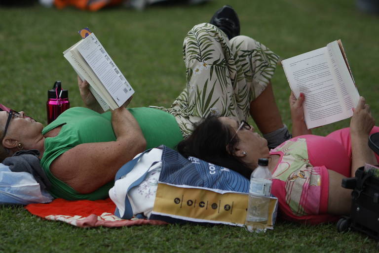 Mulheres lendo na grama deitadas