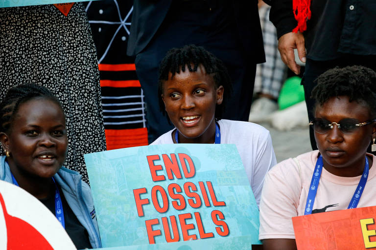 Três pessoas negras seguram cartazes que dizem 'end fossil fuels'