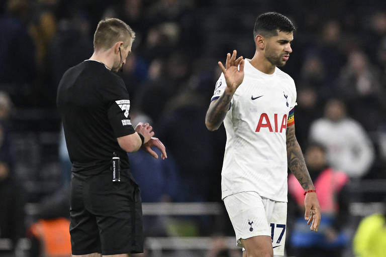 O árbitro Michael Salisbury observa seu relógio ao lado do zagueiro Cristian Romero, do Tottenham, em partida do Campeonato Inglês