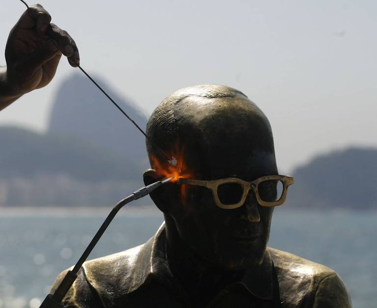 Operários recolocam par de óculos na estátua de Carlos Drummond de Andrade, que já foi furtado cinco vezes em dez meses, no Rio de Janeiro (RJ)