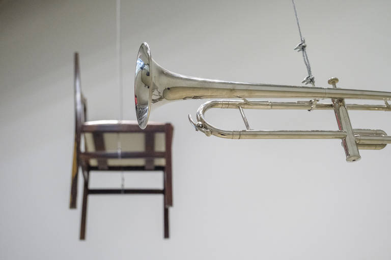 Cadeira e trompete suspensos por fios na exposição  "Espectros (Cadeira 17)", de Nuno Ramos