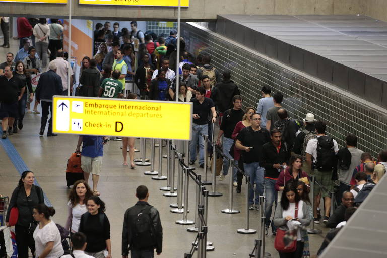 Passageiros fazem fila para entrar no setor de embarque e controle de passaporte no aeroporto de Guarulhos