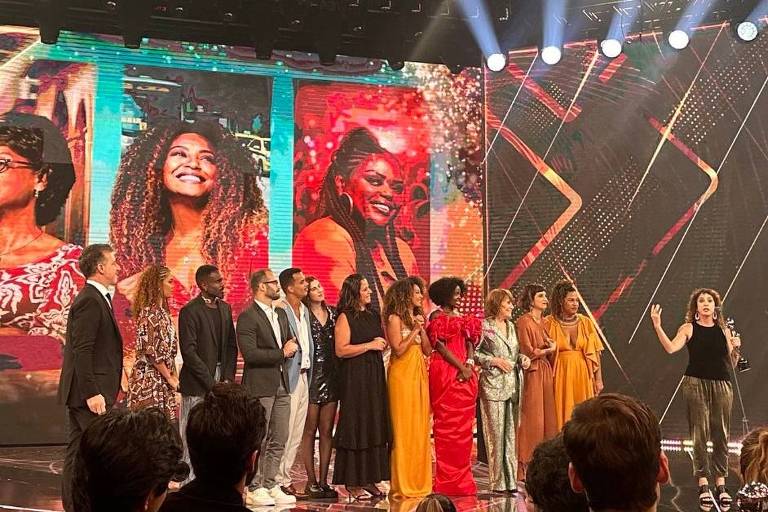 Em foto colorida, grupo de atores sobe ao palco para receber o prêmio