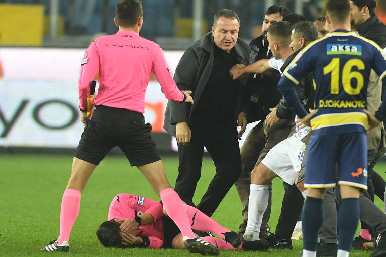 O árbitro Halil Umut Meler (de camisa e meiões cor de rosa) , caído no gramado com as mãos no rosto depois de ser esmurrado pelo presidente do Ankaragucu, Faruk Koca (de preto), em jogo do Campeonato Turco
