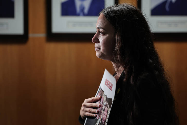 Maia Chmiel, cujos primos são mantidos reféns pelo Hamas em Gaza, segura cartaz com fotos deles durante evento no Clube Hebraica, na capital paulista, que reuniu familiares dos sequestrados; todos têm laços com a América do Sul