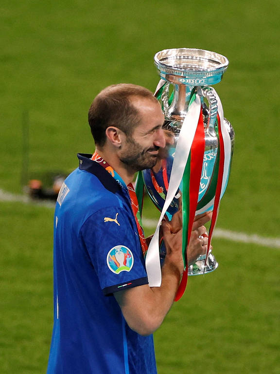 O italiano Chiellini segura e gruda o rosto na taça de campeão da Eurocopa, em 2021, no estádio de Wembley, na Inglaterra