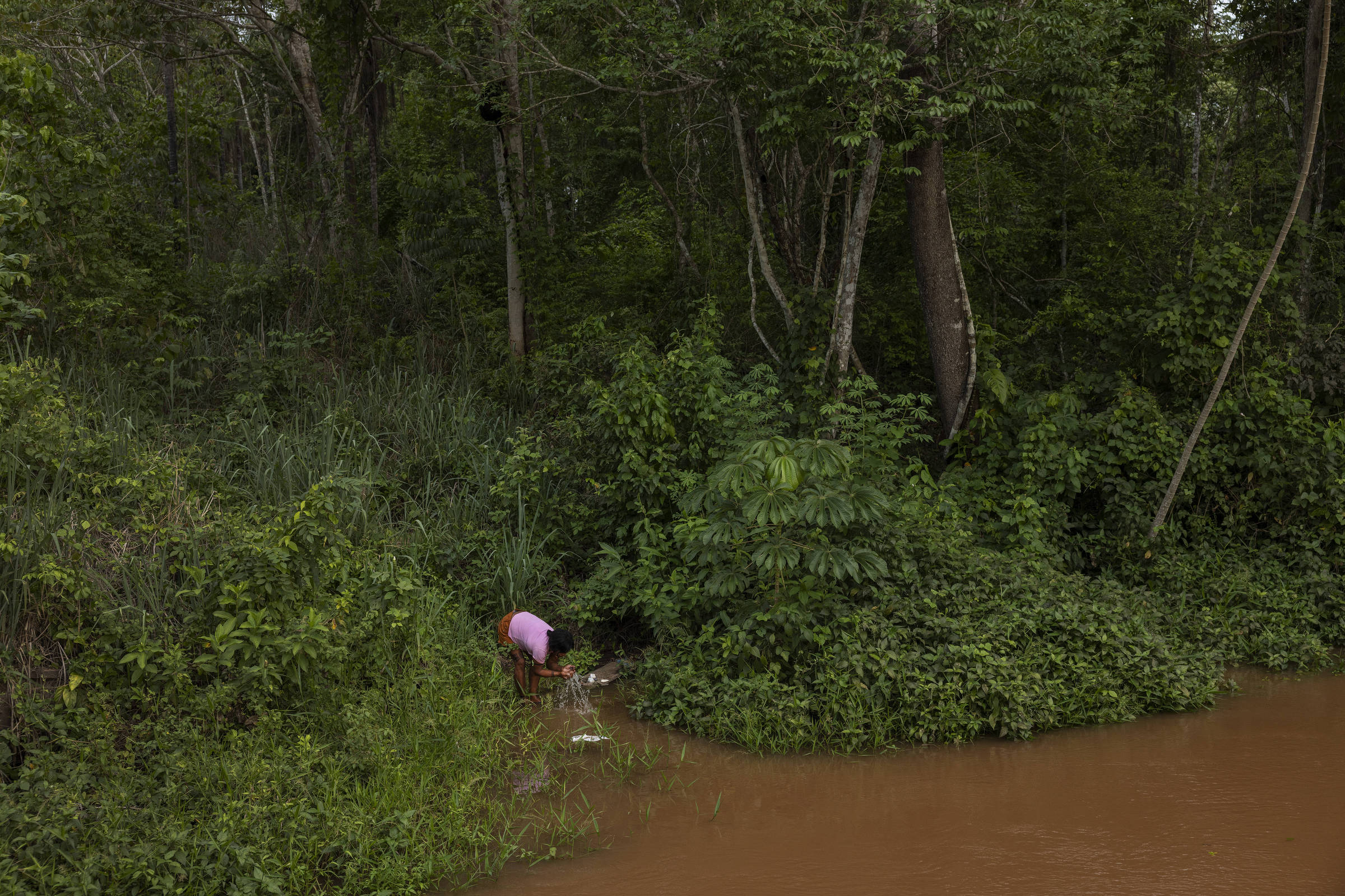Indígena na beira do rio Sararé com água suja