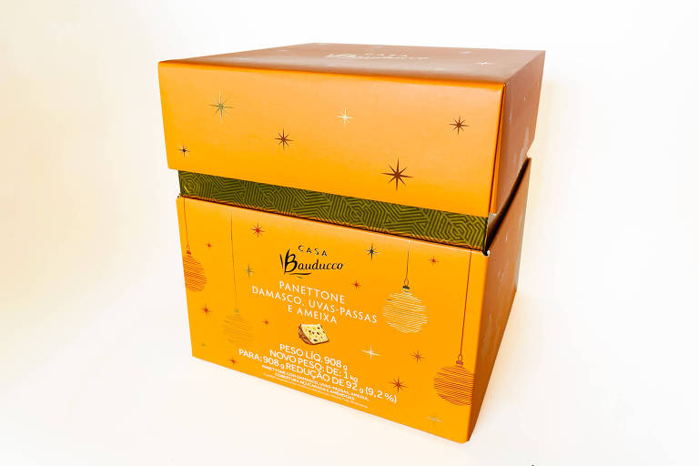 A foto mostra uma caixa de panetone na cor laranja onde se lê: Panettone damasco, uvas-passas e ameixa