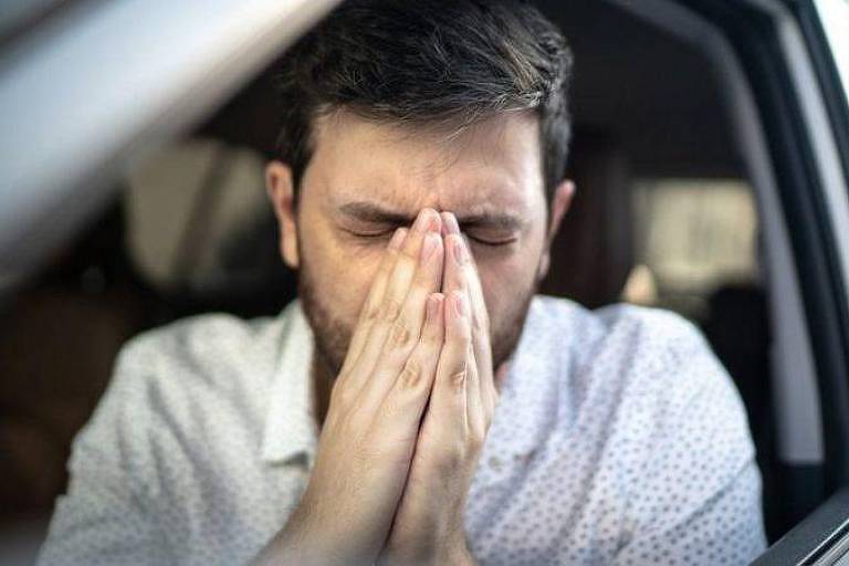 Homem branco espirrando dentro de um carro
