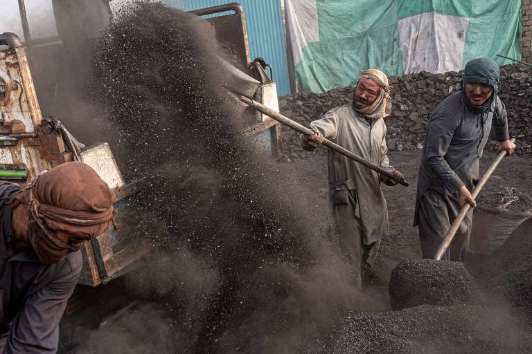 Trabalhadores carregam caminhão com carvão produzido em mina no Afeganistão
