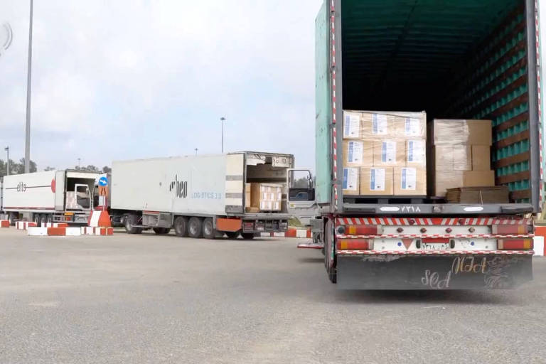 Imagem mostra uma fila de caminhões com ajuda humanitária parados em uma estrada