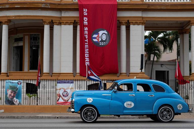 Carro passa por bandeira dos Comitês de Defesa da Revolução (CDR) em Havana, a capital de Cuba