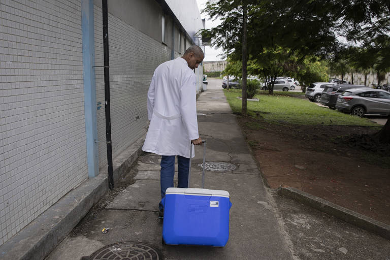 Gilberto carrega cooler com o órgão pelo estacionamento do hospital, onde fica o heliponto