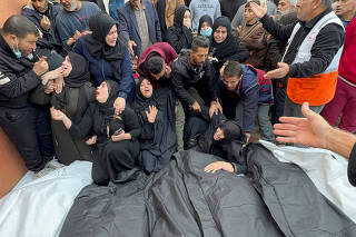 People react next to the bodies of Palestinians killed in Israeli strikes, at Nasser hospital, in Khan Younis