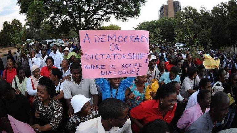 Manifestação em Botsuana; um dos manifestantes segura cartaz questionando a falta de diálogo social