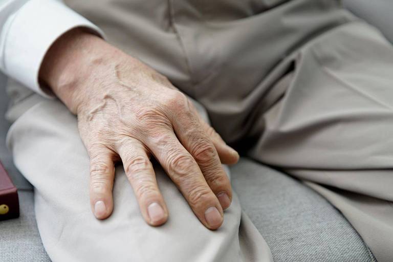 Foto destaca mão de idoso apoiada em suas coxas