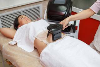 Woman getting cryolipolysis fat treatment in professional cosmetic cabinet