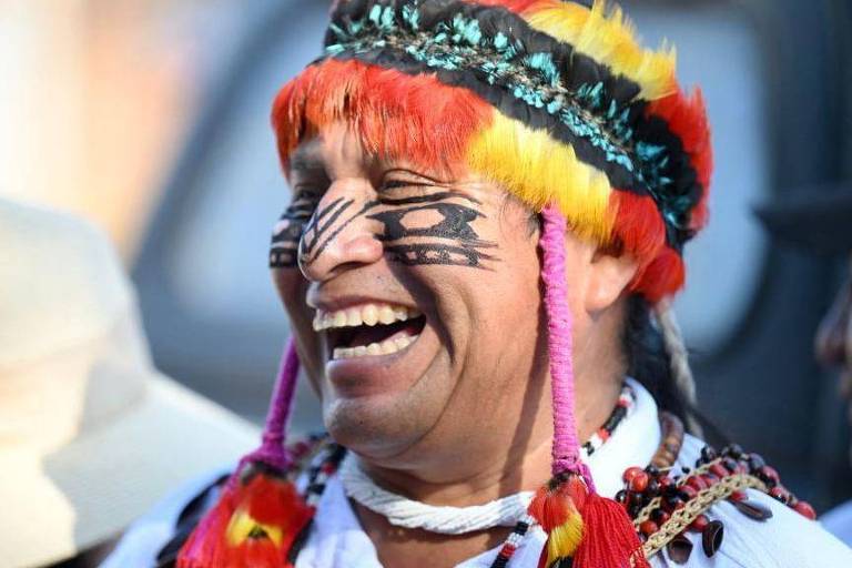 Indígena sorrindo em imagem de perfil.