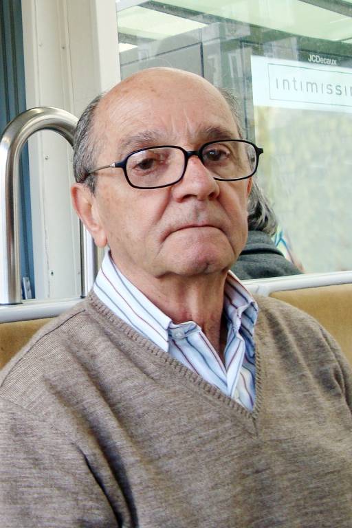 Homem de óculos sentado com blusa marrom claro