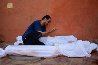 Palestinian man Mohammed al-Akhras reacts next to the bodies of his daughter Jana and his wife who were killed by Israeli strikes, in Khan Younis