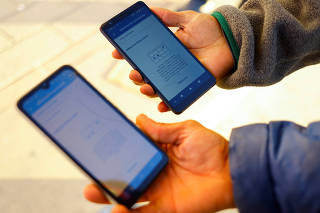 Migrants seeking asylum in the U.S. use their phones to request an appointment at a land port of entry to the U.S., in Ciudad Juarez